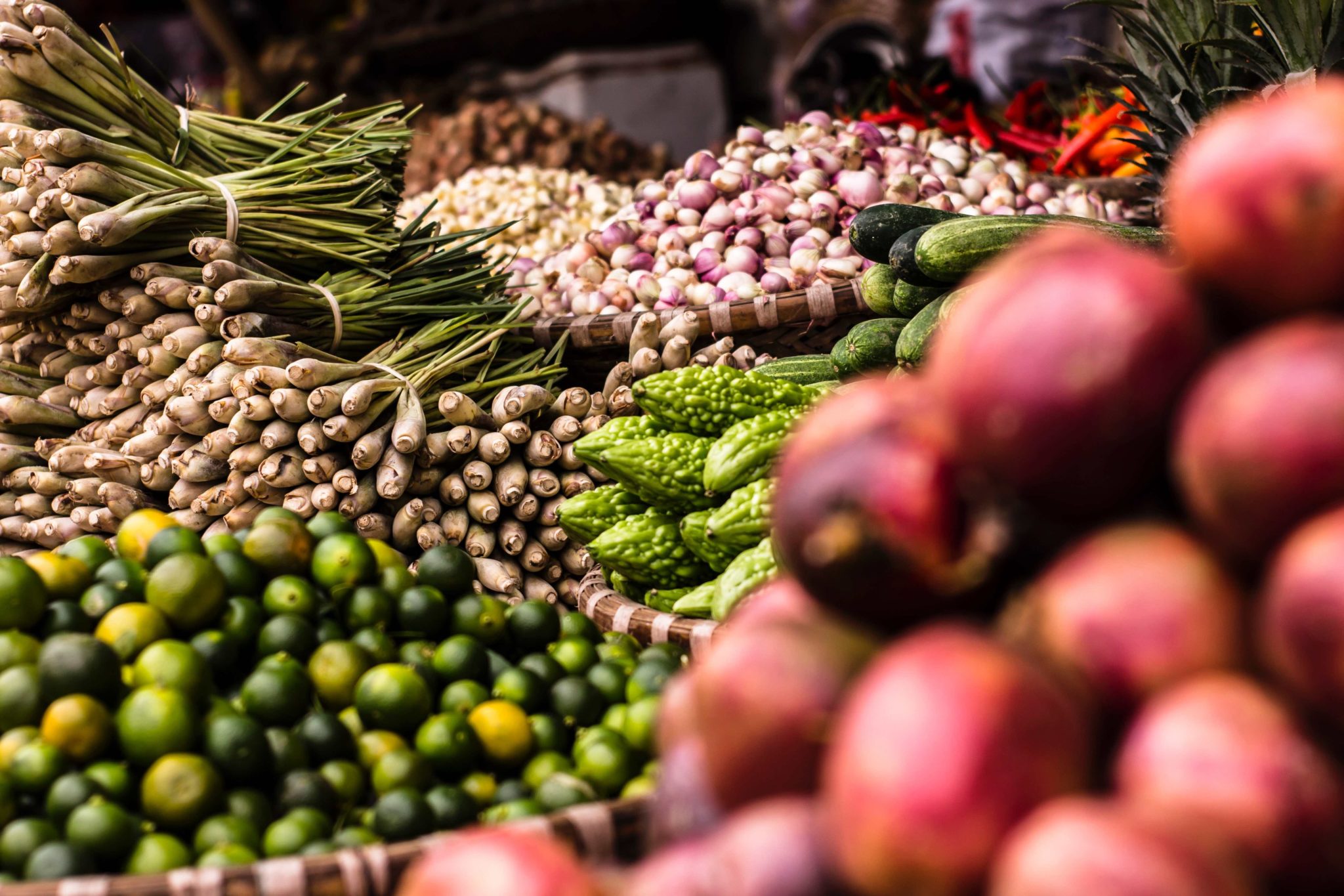 Piles of produce at a warehouse, including potatoes, limes, and asparagus.