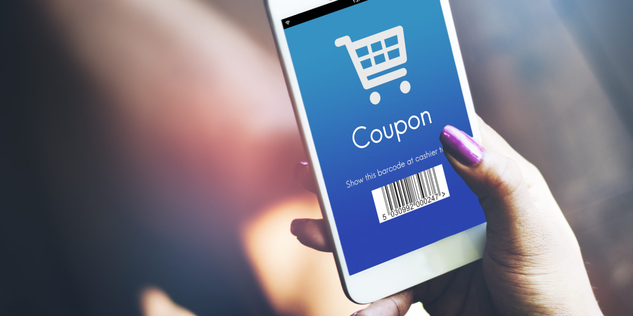 A woman scans a mobile coupon from an eCommerce loyalty program app on her smartphone to save money while shopping in-store.